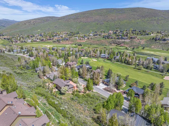Aerial perspective of suburban area featuring a mountain backdrop and a golf course