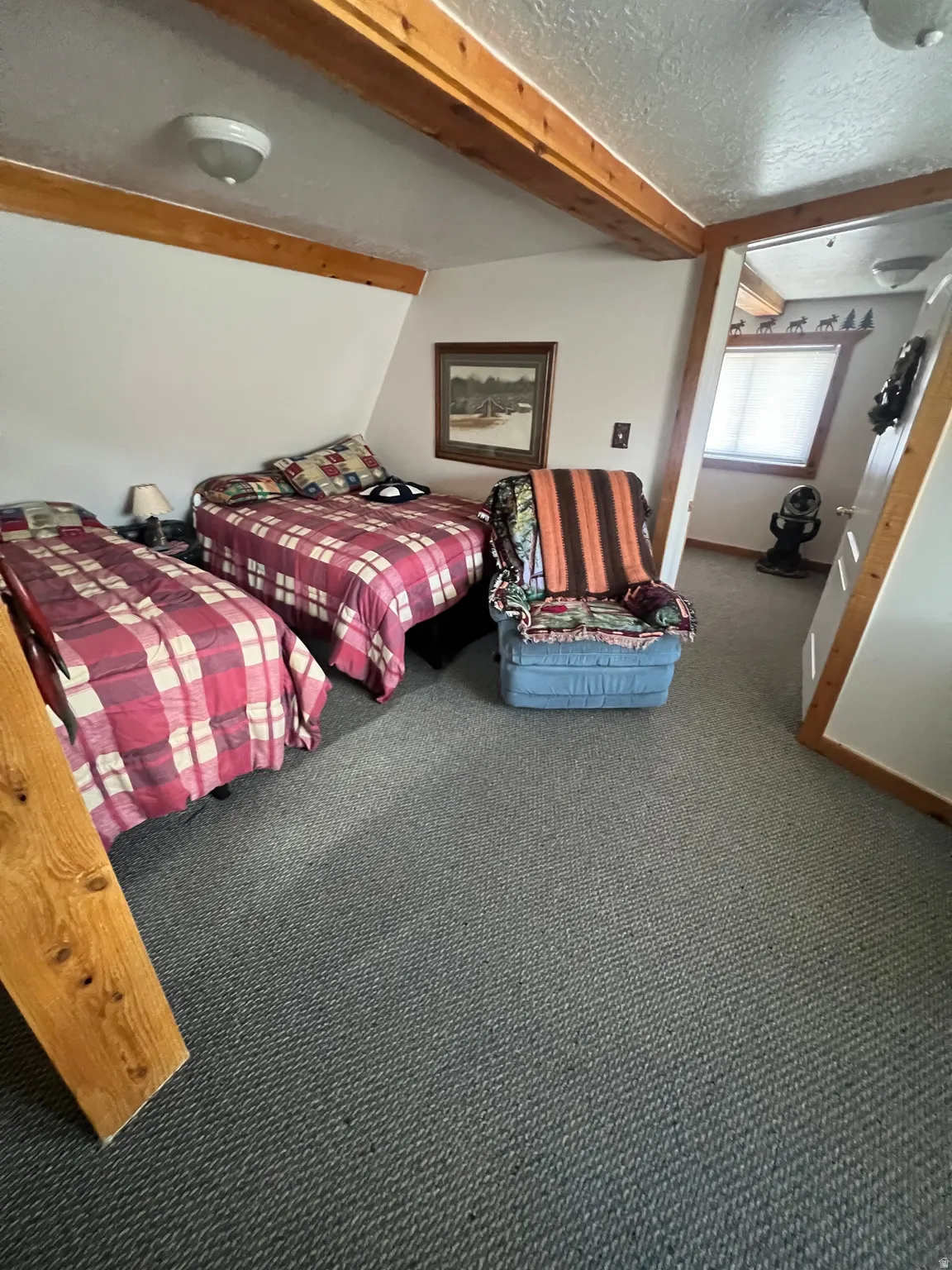 Carpeted bedroom #1 with beam ceiling and a textured ceiling