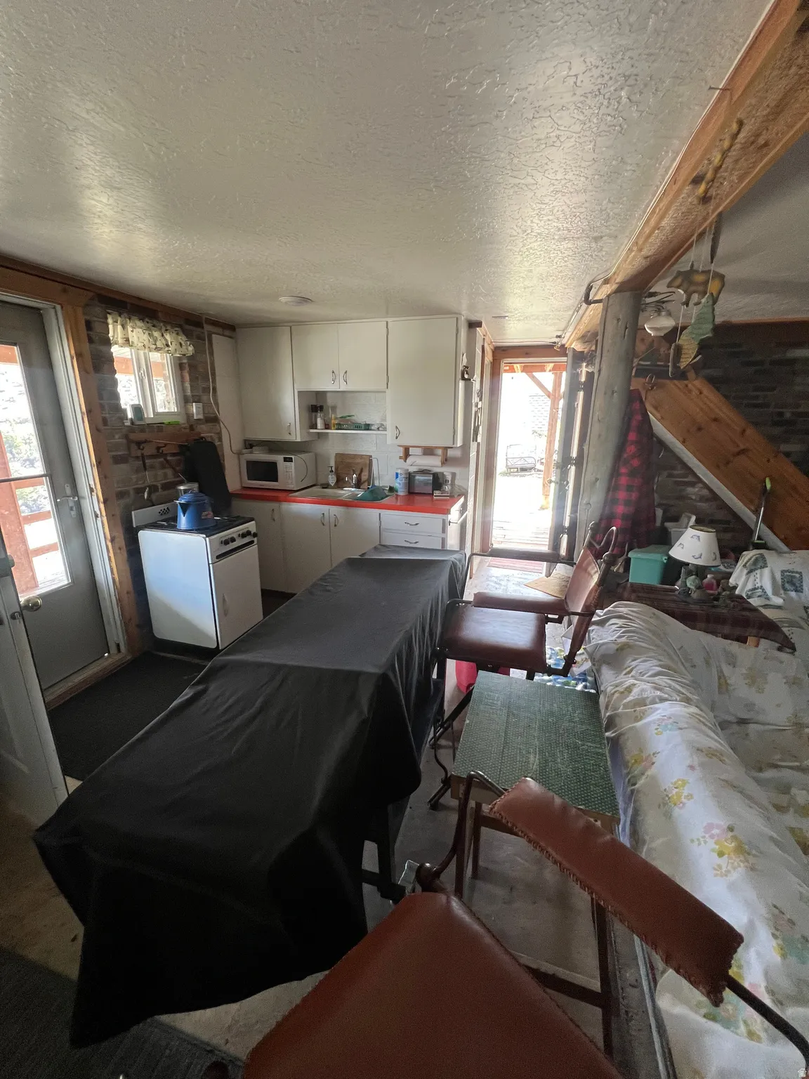 Kitchen with white appliances, white cabinetry, and a textured ceiling