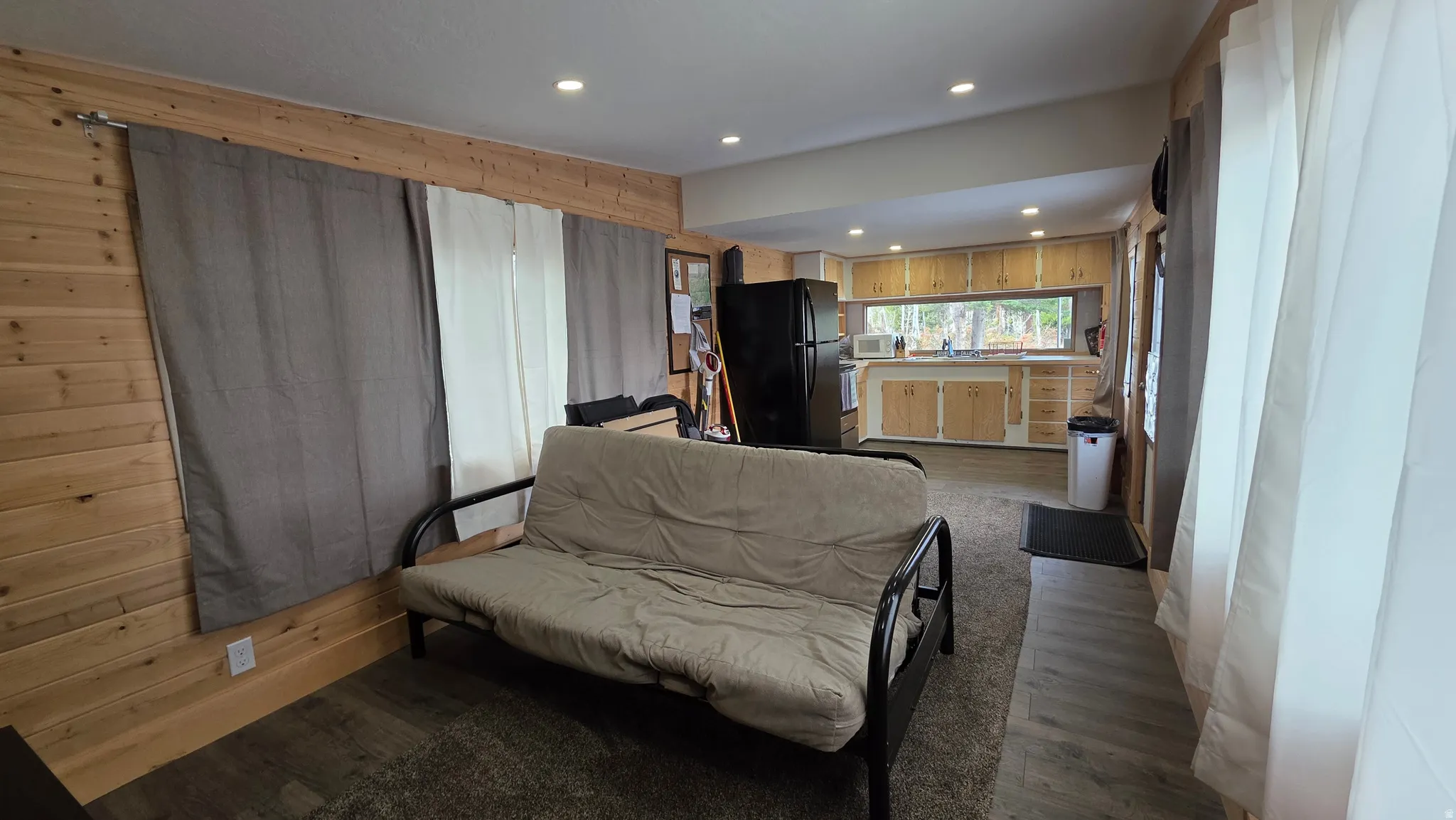 Living area featuring dark wood-type flooring, recessed lighting, and wooden walls
