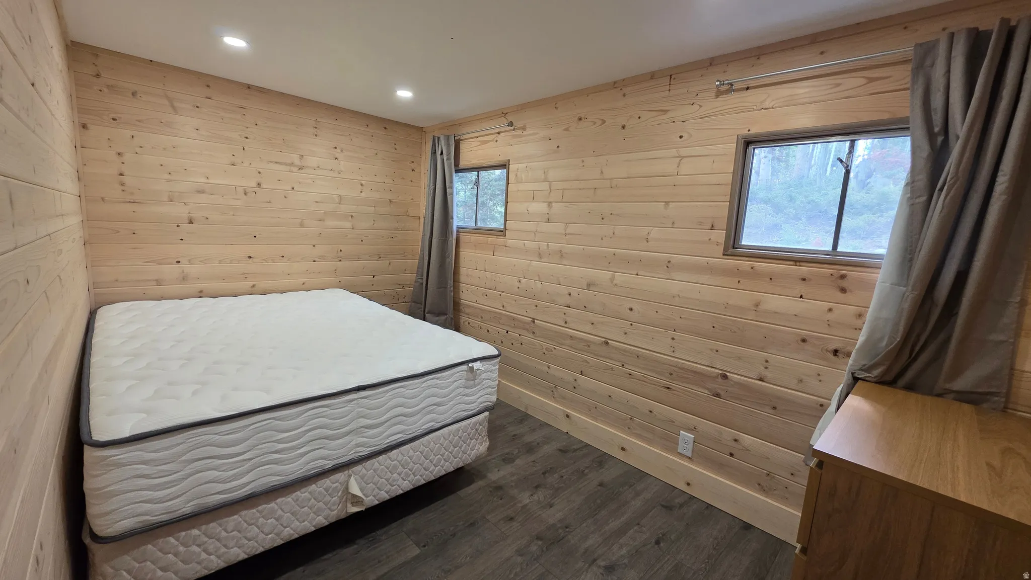 Bedroom featuring wood walls, dark wood-type flooring, and recessed lighting
