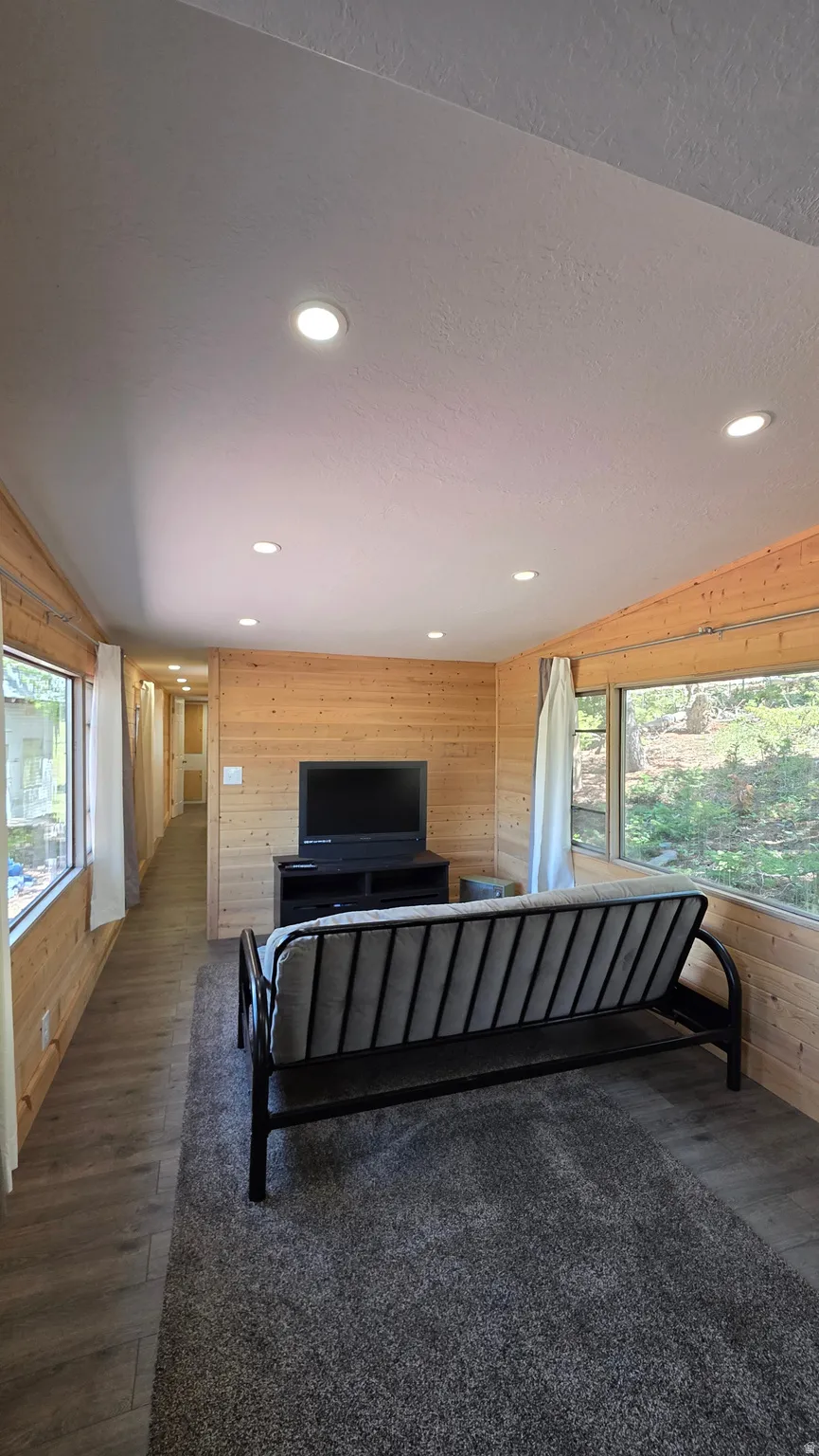 Open-concept living area featuring wood-finish flooring, natural wood paneling, and recessed ceiling lighting