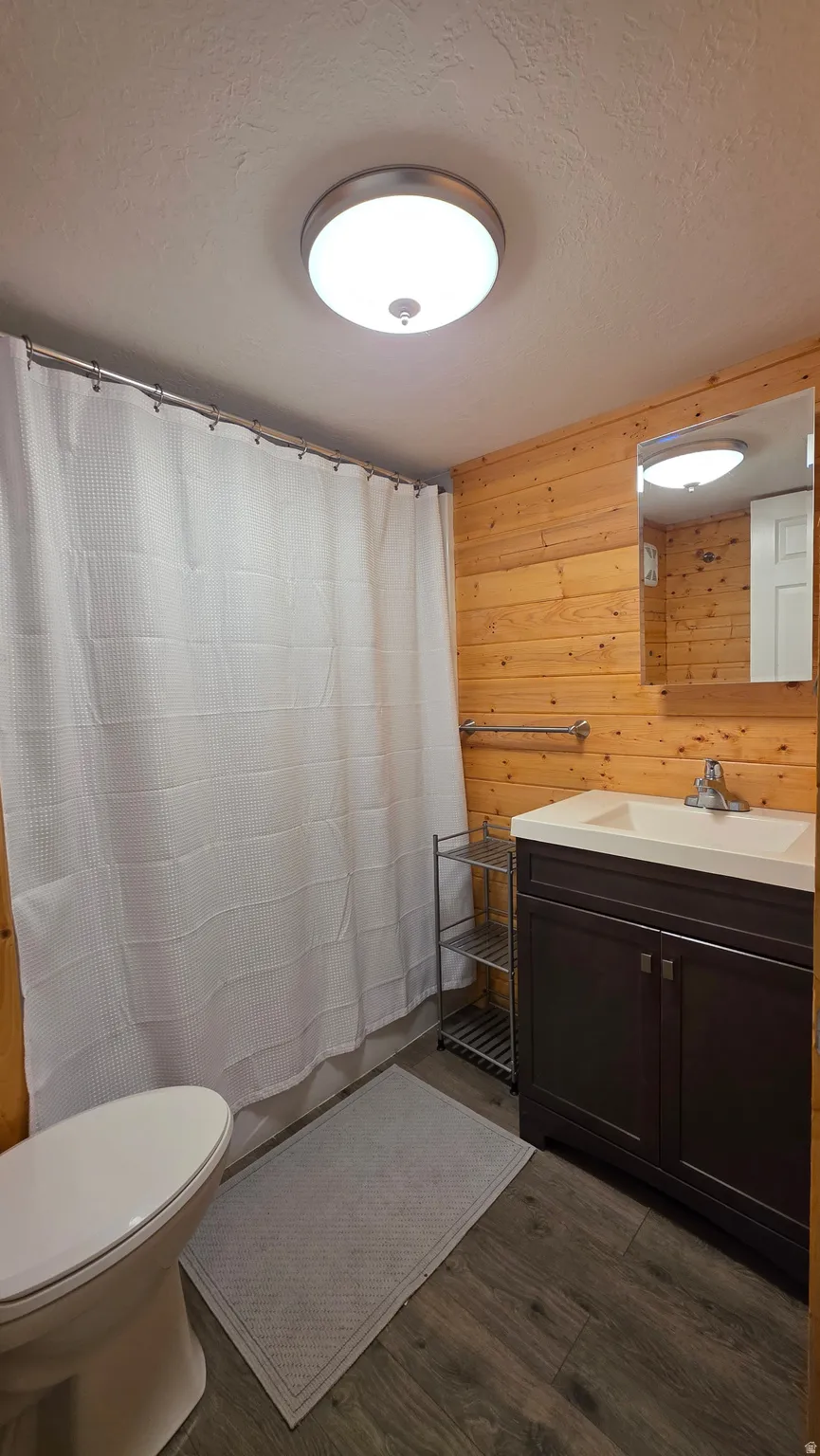 Bathroom featuring wood-finish flooring and wood paneling on walls