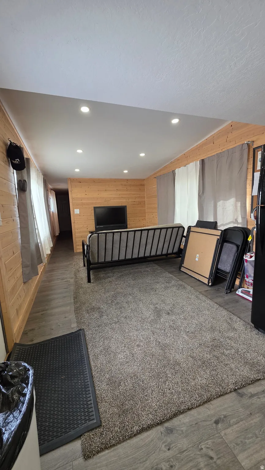 Miscellaneous room featuring wooden walls, dark wood-style floors, and recessed lighting