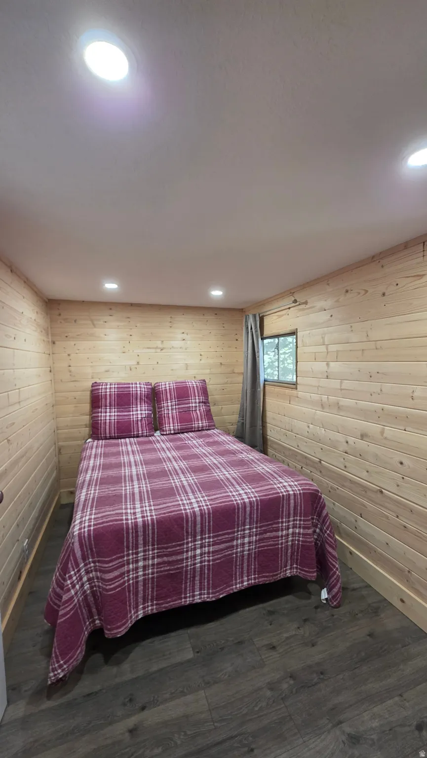 Room featuring plank-style wood walls, grey wood-finish flooring, and recessed ceiling lighting