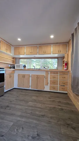 Kitchen featuring wood-finish flooring, extensive natural wood cabinetry, recessed lighting, and a wide window above the sink