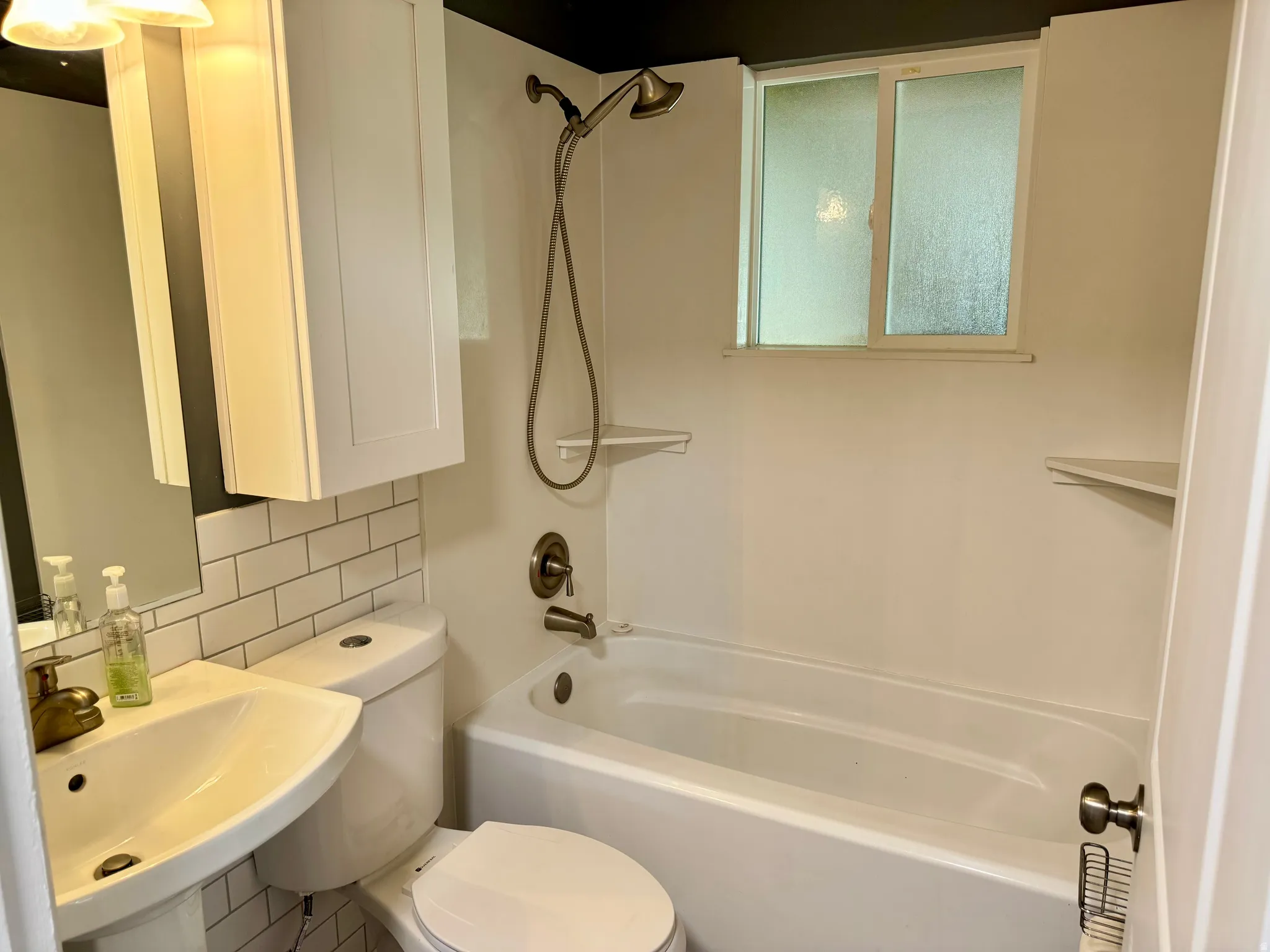 Bathroom featuring bathtub / shower combination and tasteful backsplash