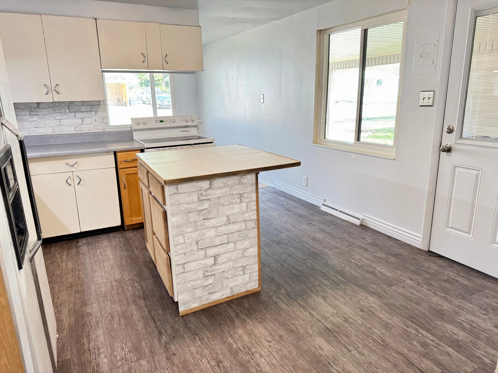 Kitchen with white appliances, dark wood-style floors, and a center island