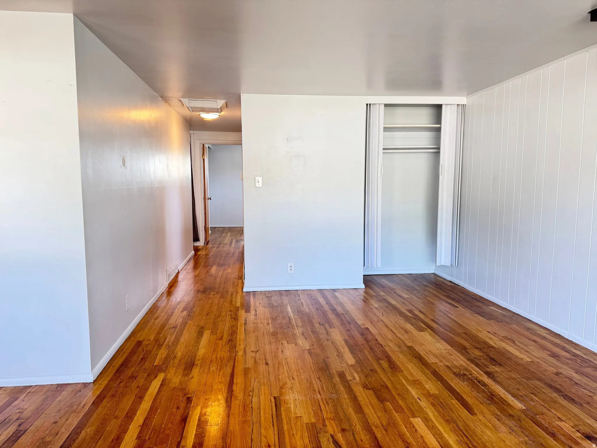 Unfurnished bedroom with dark wood-type flooring, a closet, and cooling unit