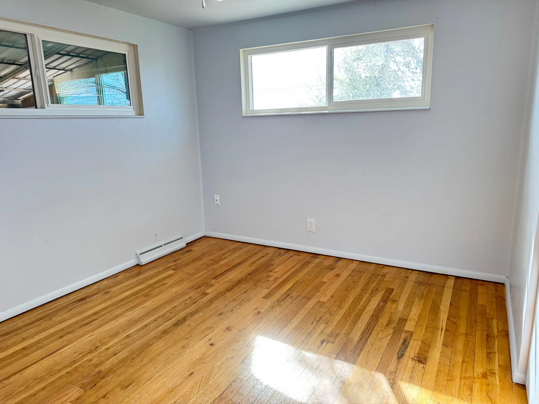 Unfurnished room with light wood-type flooring, healthy amount of natural light, and baseboard heating