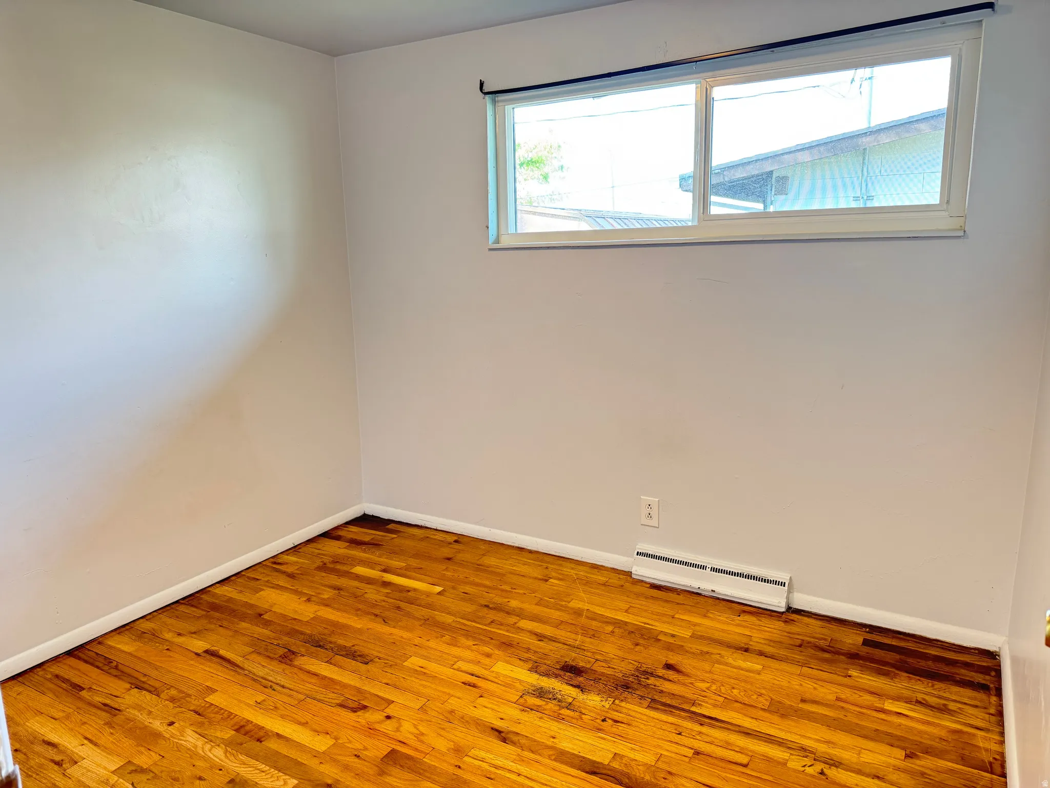 Unfurnished room with hardwood / wood-style floors and a baseboard radiator