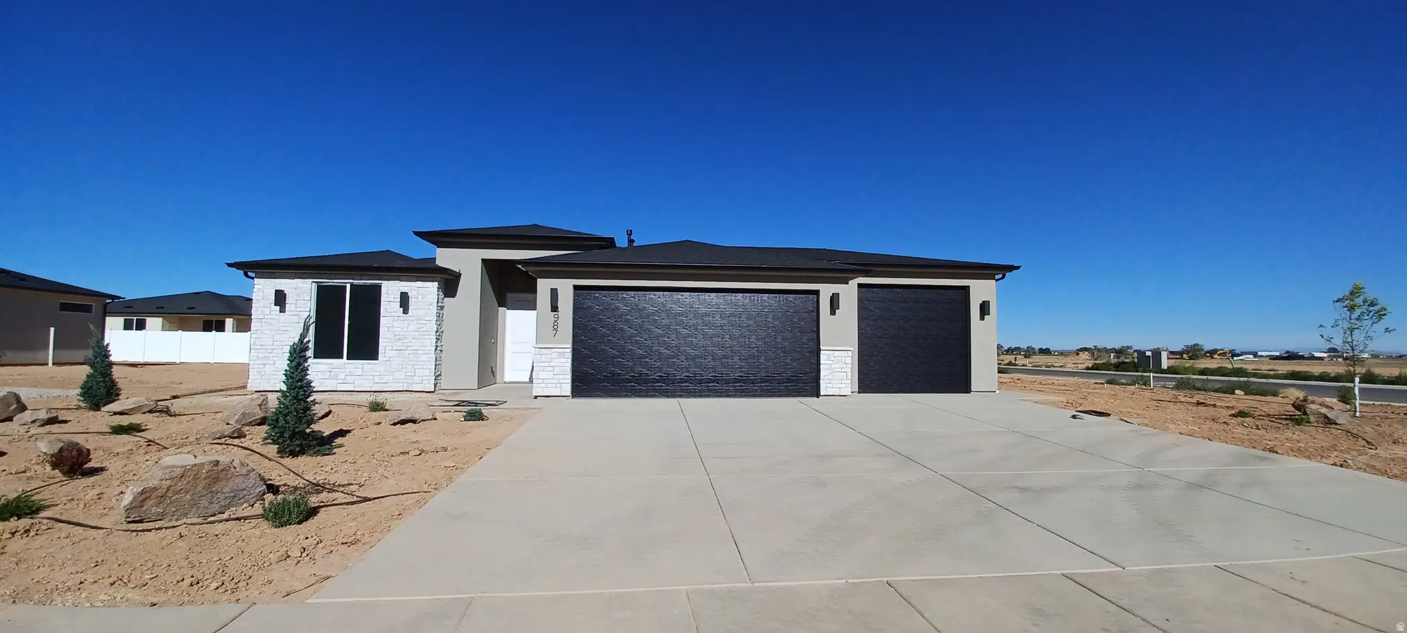 Contemporary exterior featuring a smooth stucco finish with white stone accents and a dark roof