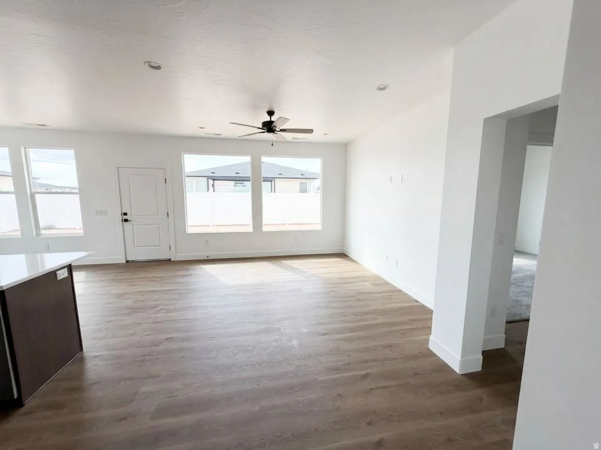 Expansive living area with wood-finish flooring, recessed lighting, and a ceiling fan