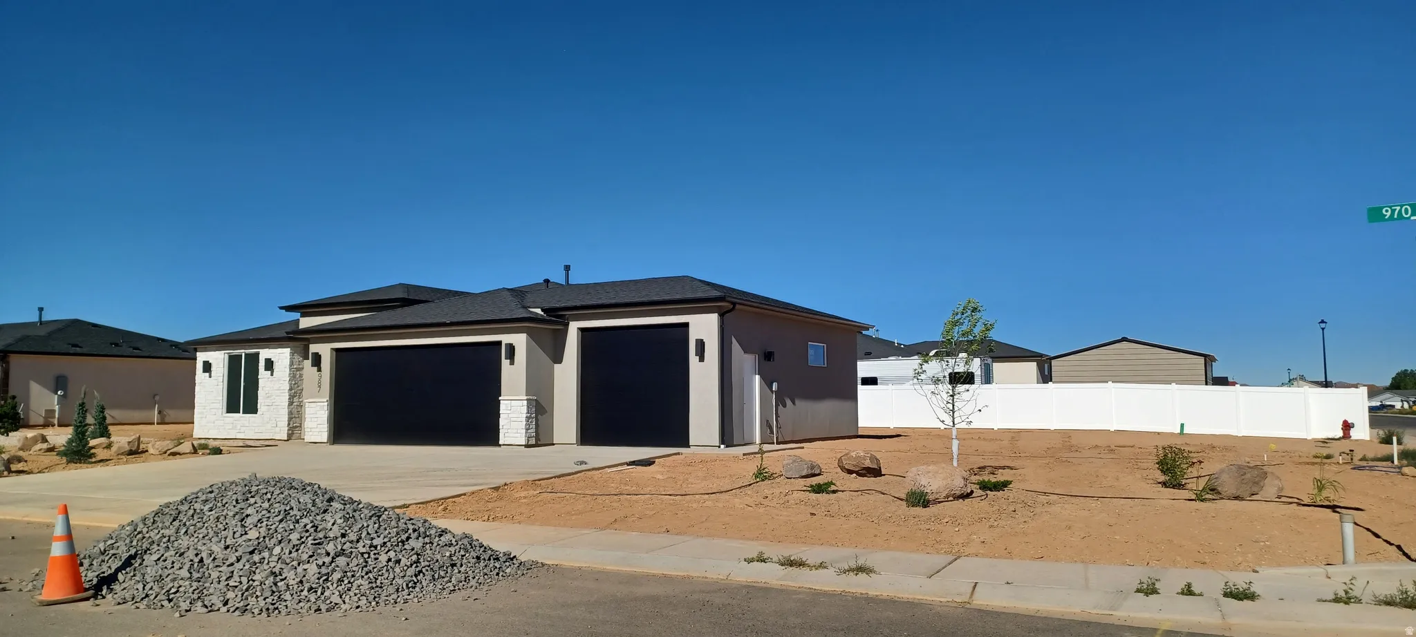 Contemporary stucco exterior with a multi-car garage featuring black garage doors, complemented by stone accents and dark trim
