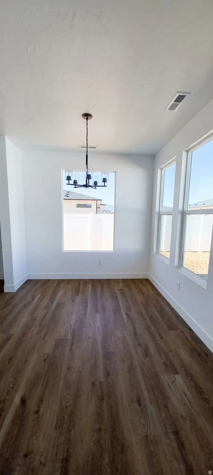 Wood-finish flooring, multiple large windows, flush-mount lighting fixture, and white wall finishes
