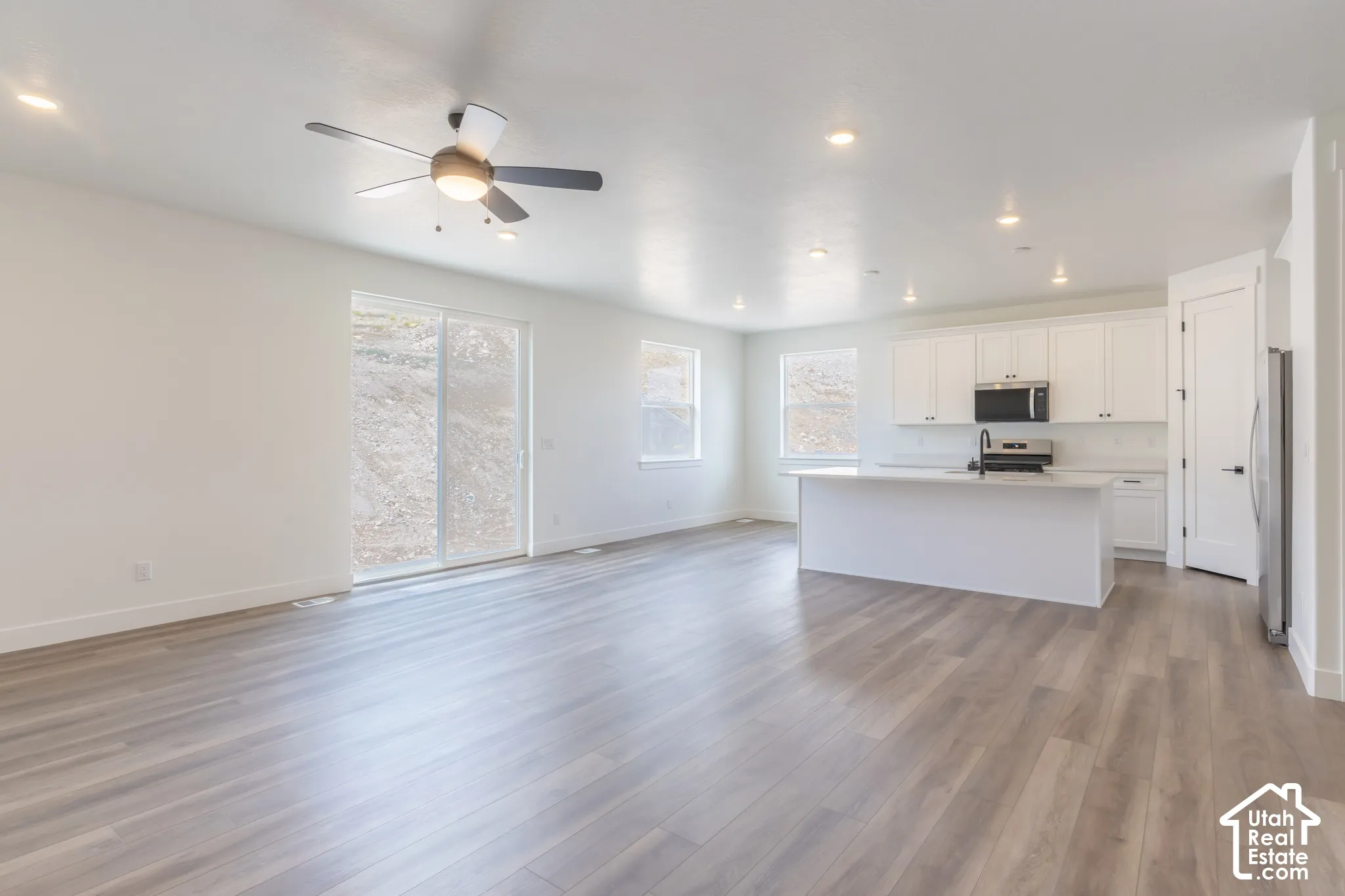Open-concept living area featuring wood-finish flooring, recessed lighting, and a ceiling fan