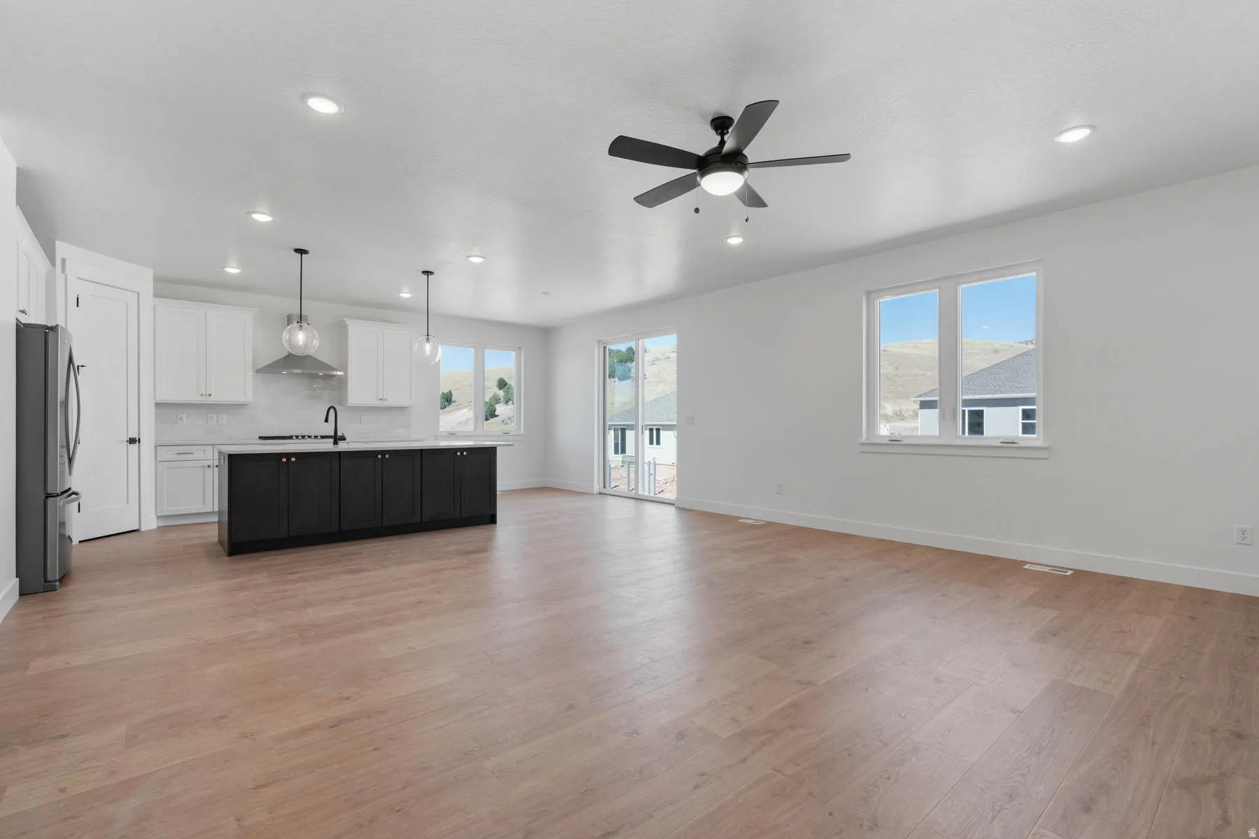 Unfurnished living room featuring light wood-style floors, ceiling fan, plenty of natural light, and recessed lighting