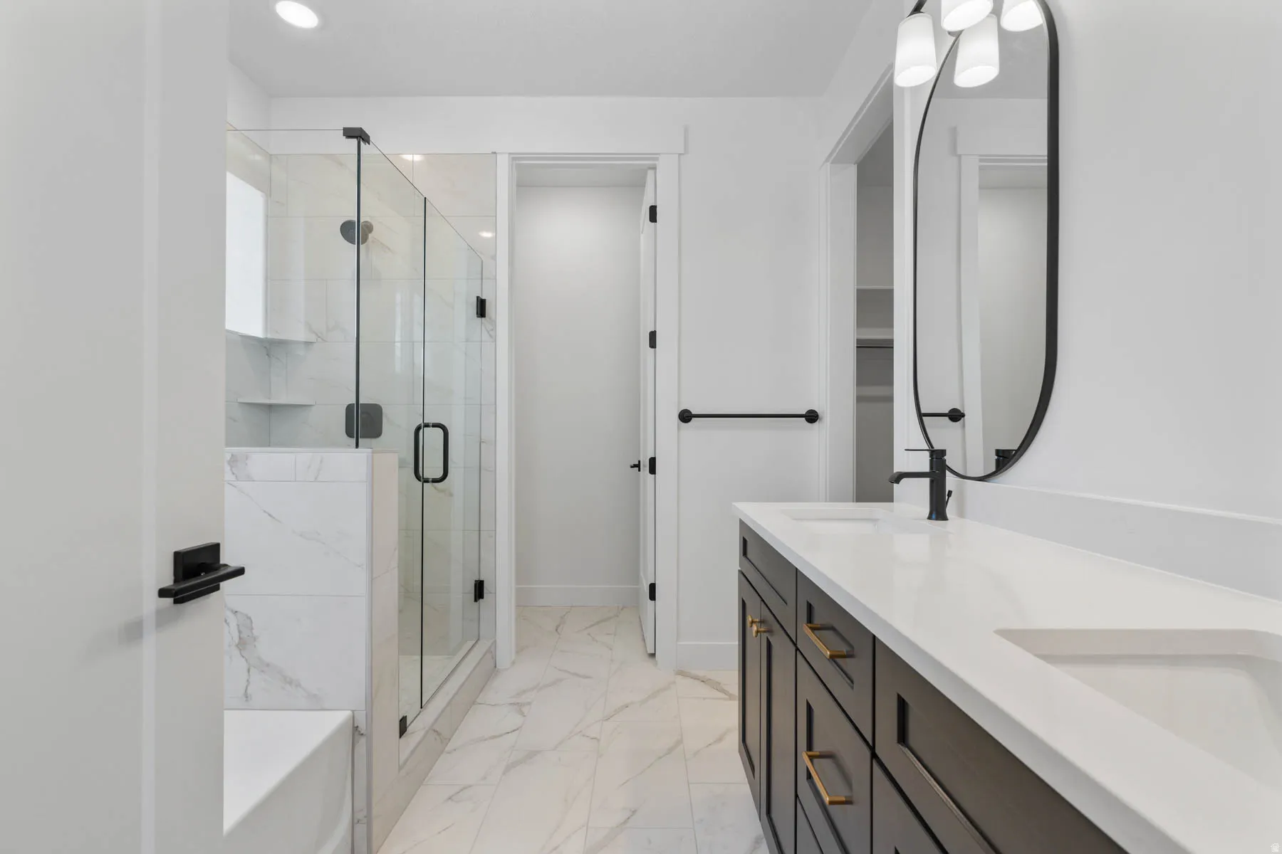 Bathroom featuring double vanity, a marble finish shower, light marble finish flooring, and recessed lighting