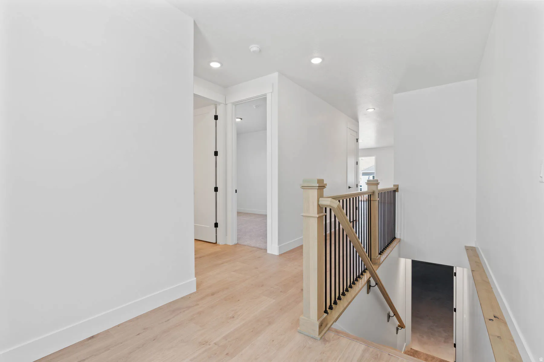 Hallway with an upstairs landing, light wood-style flooring, and recessed lighting
