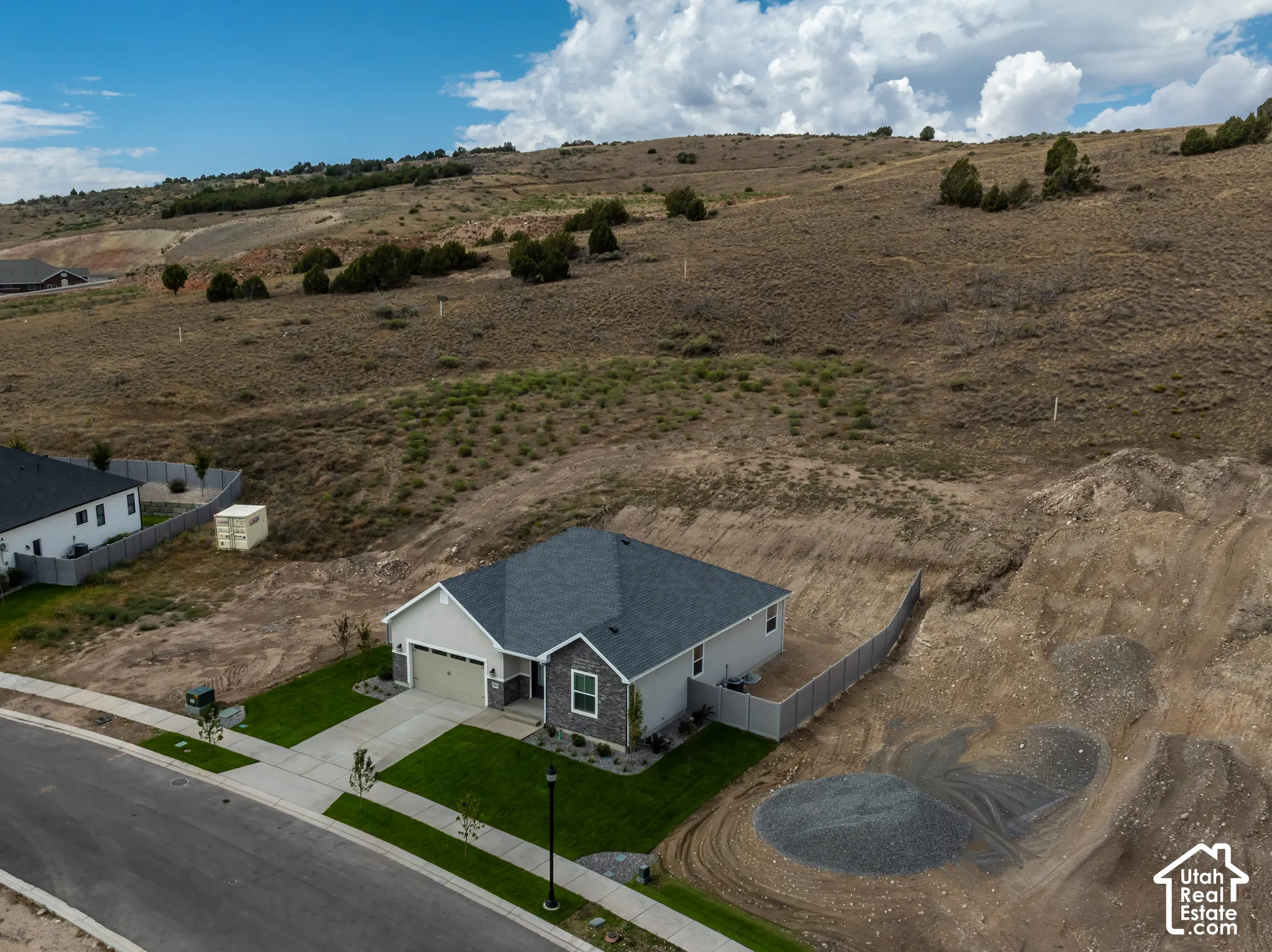 Single-story residence with an attached garage, featuring a dark gray roof and light-colored siding with stone accents