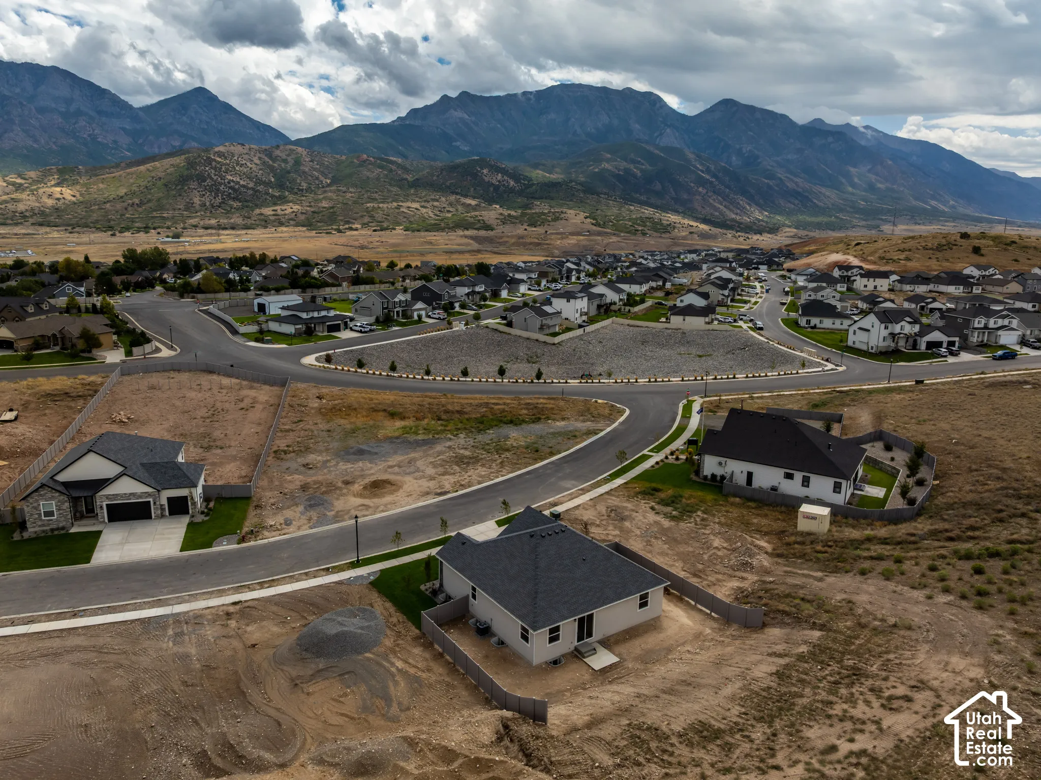 New construction homes situated within a developing neighborhood, featuring paved roads and mountain scenery