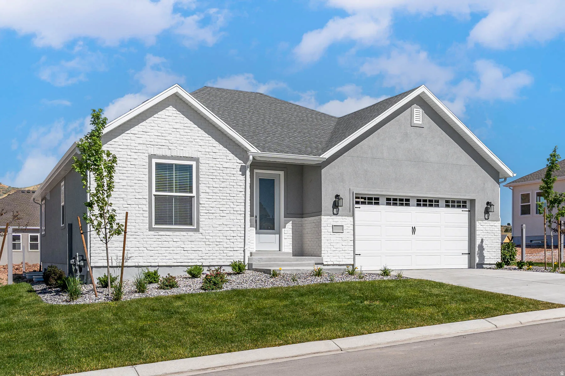 View of front of house with an attached garage, a front yard, concrete driveway, and stucco siding
