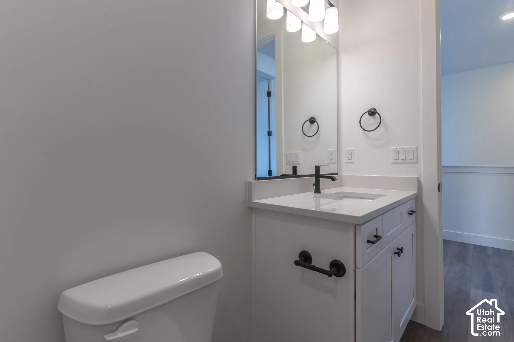 White vanity with a built-in sink, dark hardware, and a wall-mounted mirror