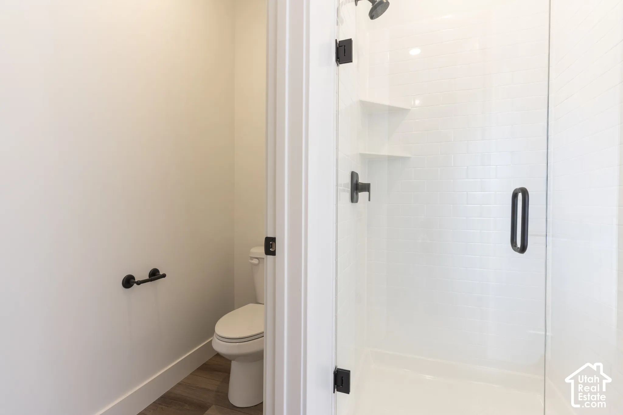 Shower enclosure with clear glass panel, matte black hardware, and white subway tile surround
