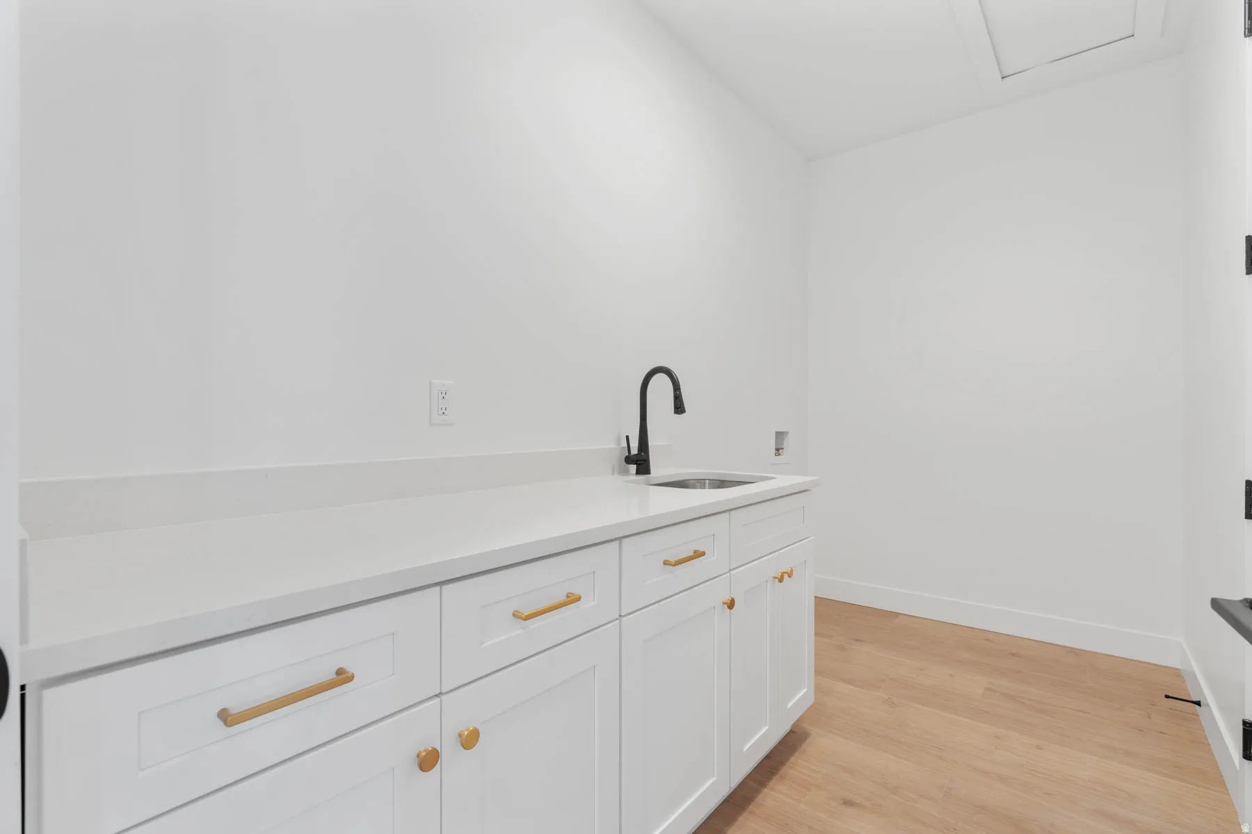 Bar featuring white cabinetry, light wood-style floors, and light stone counters