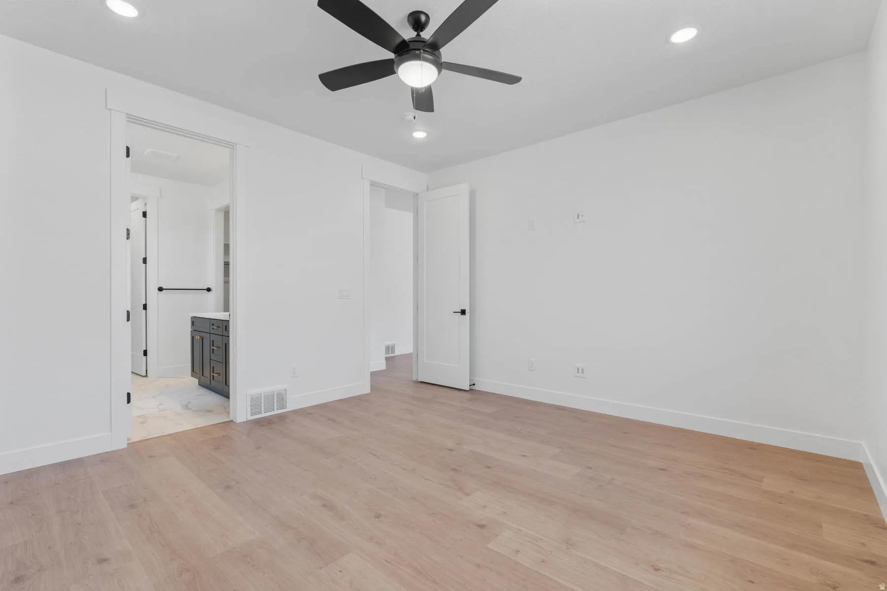 Unfurnished bedroom with light wood-type flooring, recessed lighting, ceiling fan, and ensuite bathroom