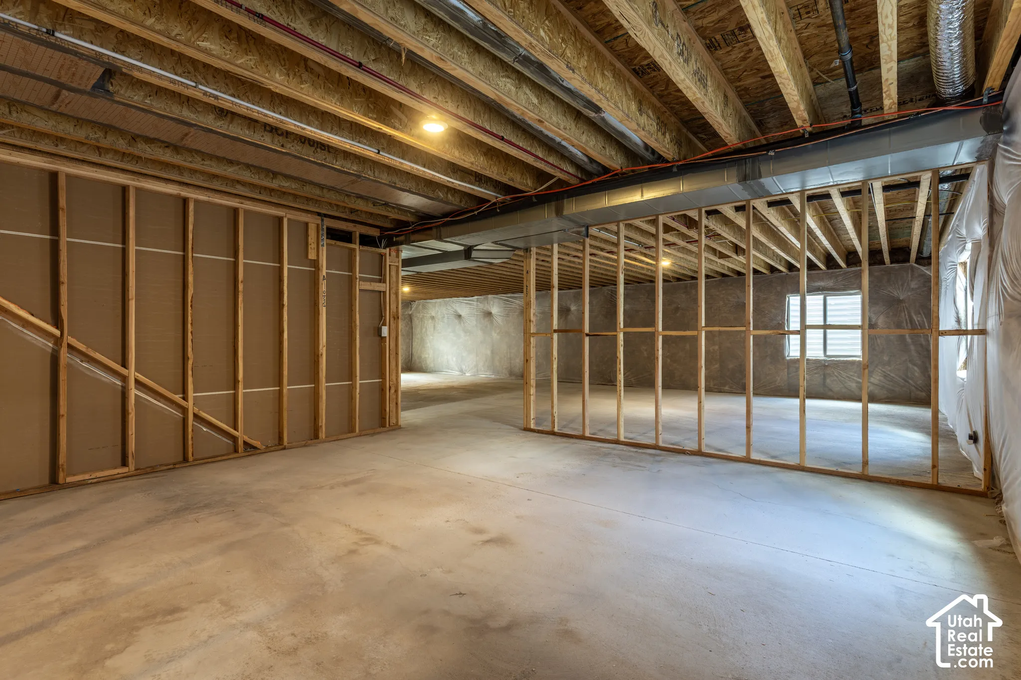Unfinished basement featuring exposed wood joists, concrete flooring, and framed partition walls
