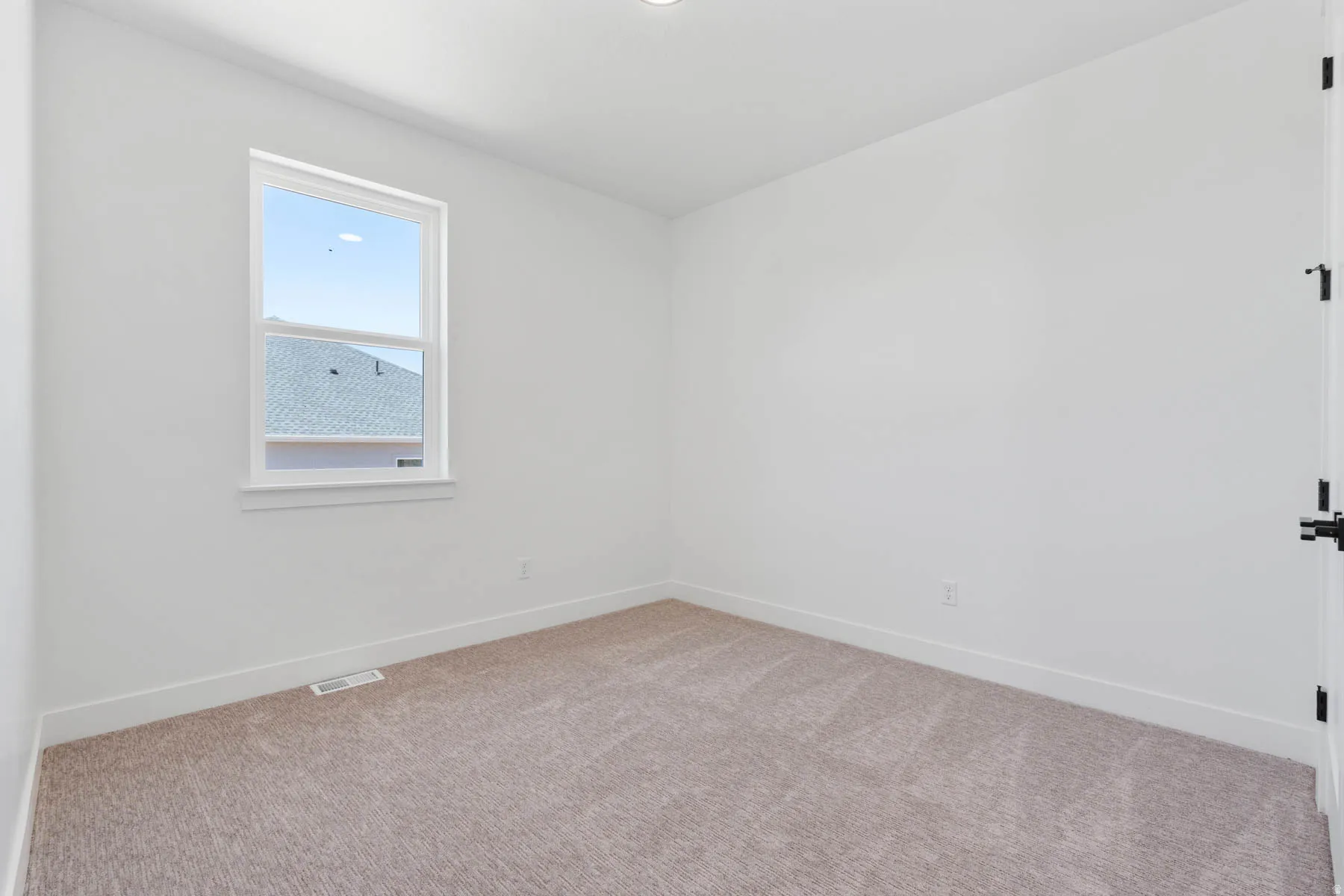 Carpeted spare room featuring baseboards