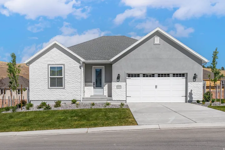 Single story home with a garage, concrete driveway, stucco siding, and a front yard