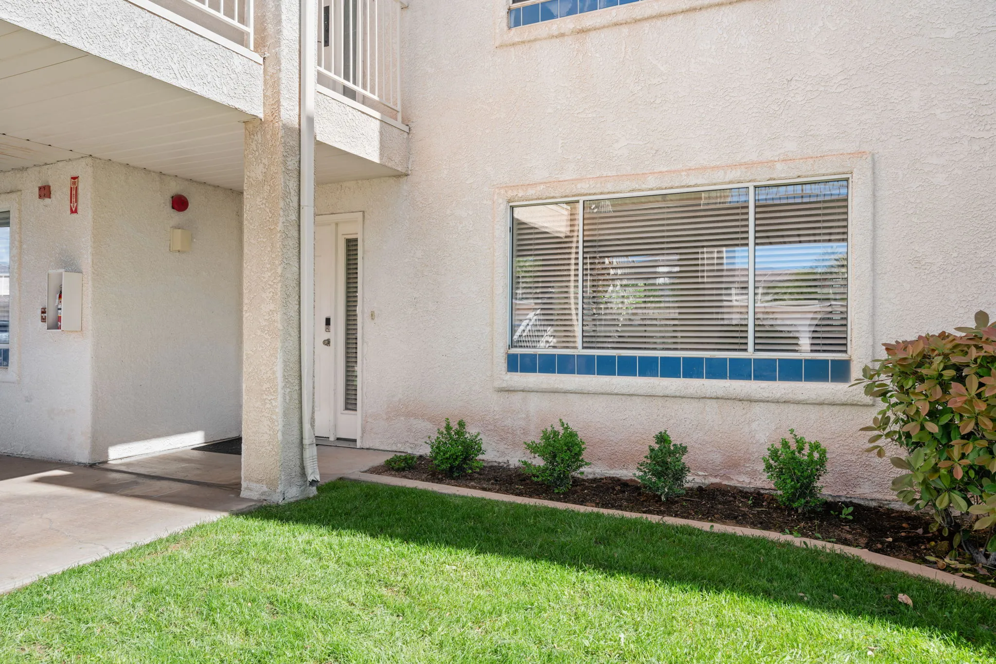 View of exterior entry featuring stucco siding and a lawn
