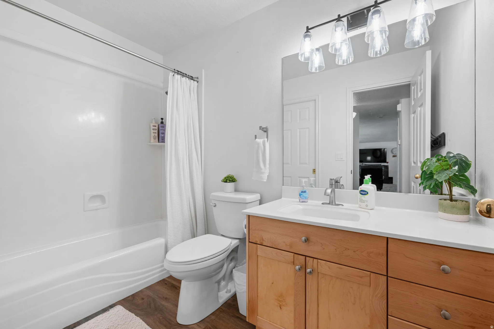 Bathroom with vanity, dark wood-style flooring, and shower / bath combination with curtain