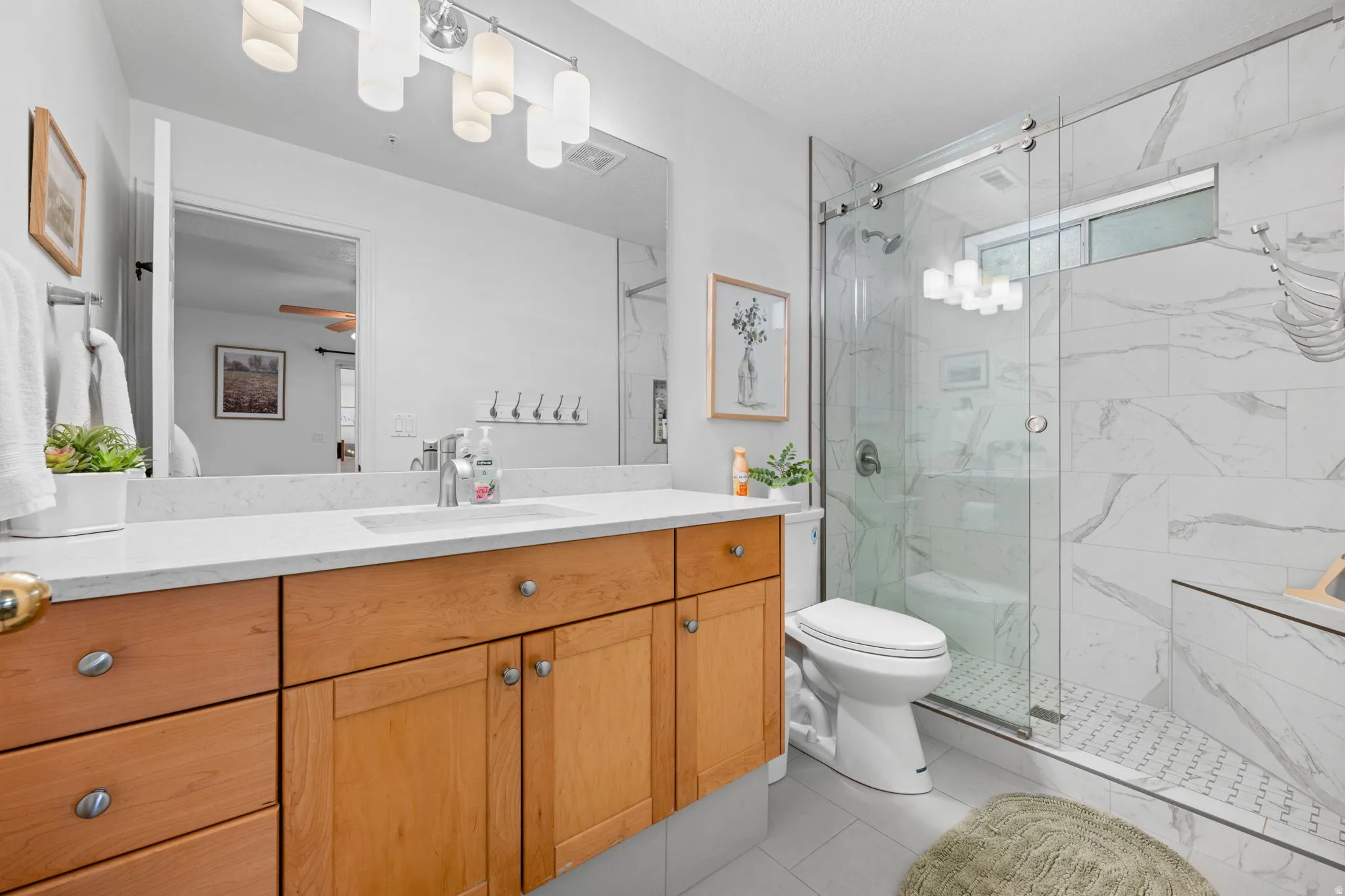 Bathroom featuring vanity, a marble finish shower, and light tile patterned flooring