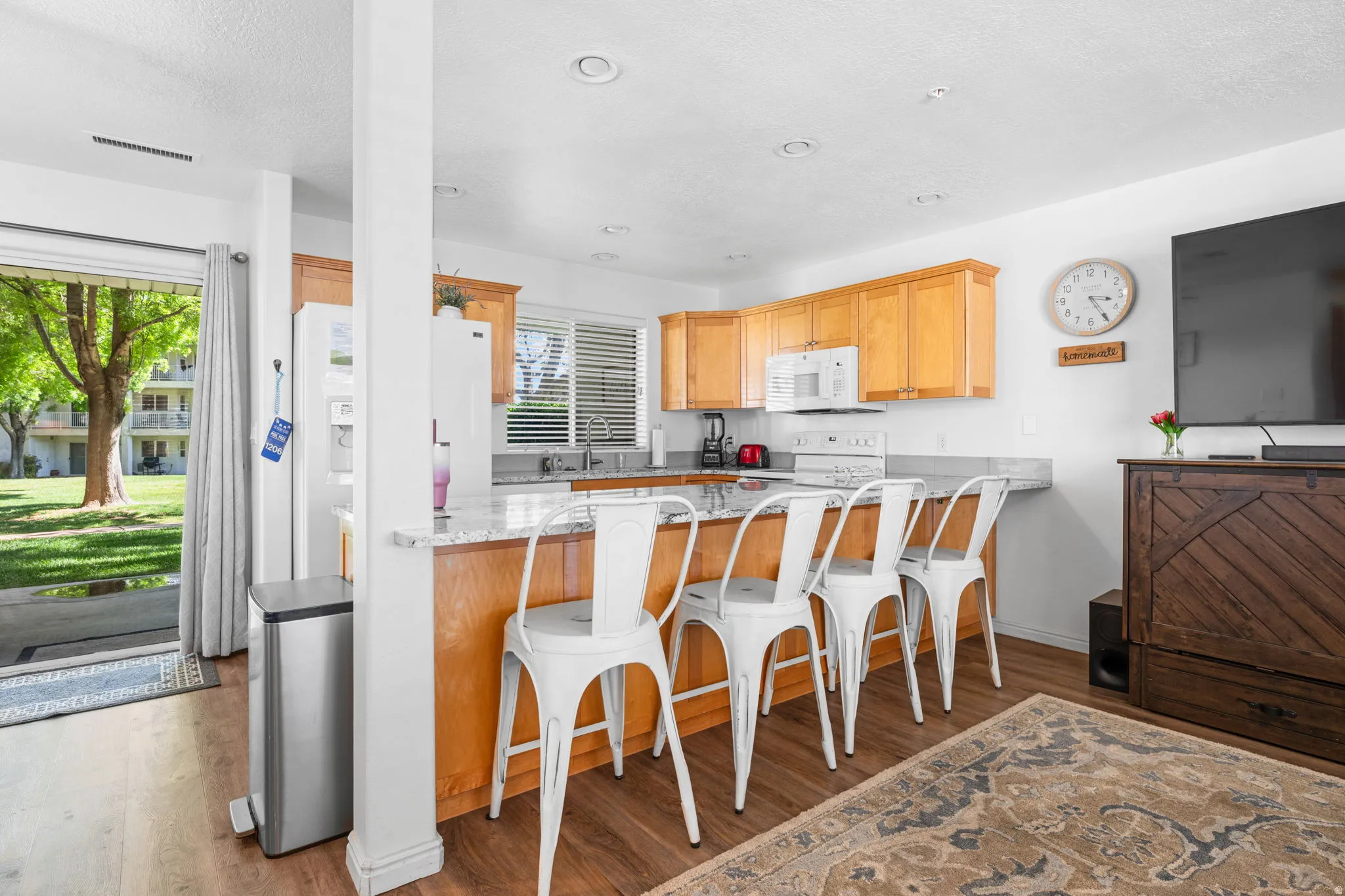 Kitchen featuring a peninsula, a breakfast bar area, dark wood finished floors, and light stone countertops