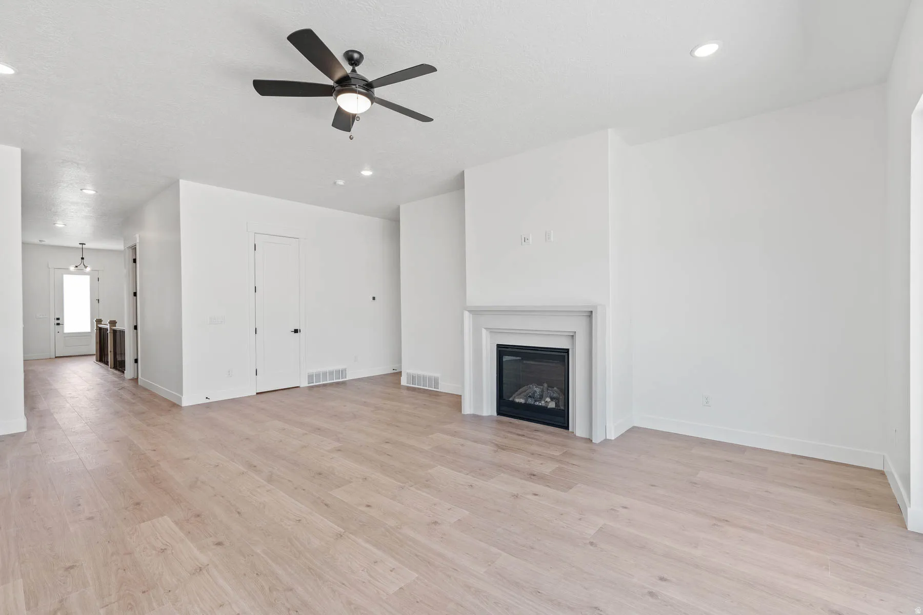 Unfurnished living room with ceiling fan, a glass covered fireplace, recessed lighting, and light wood finished floors