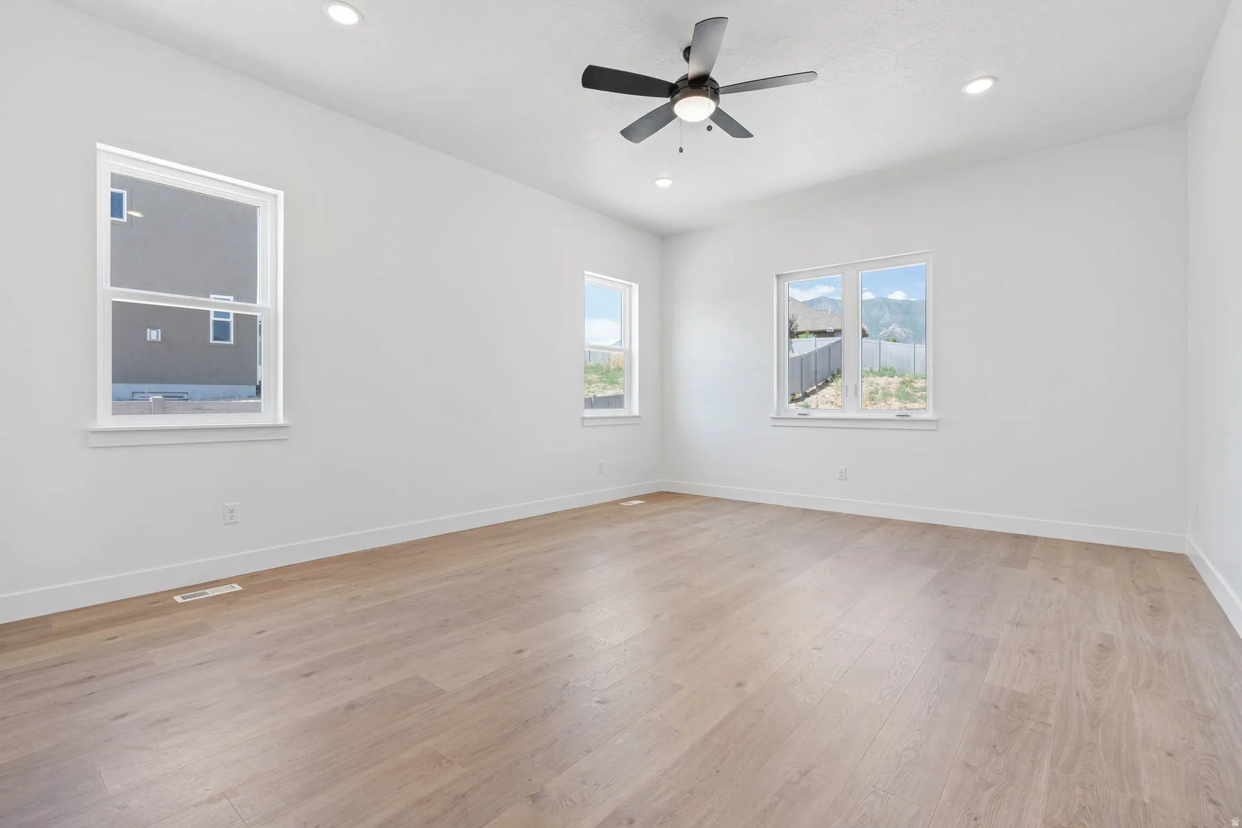 Empty room with light wood-type flooring, ceiling fan, and recessed lighting