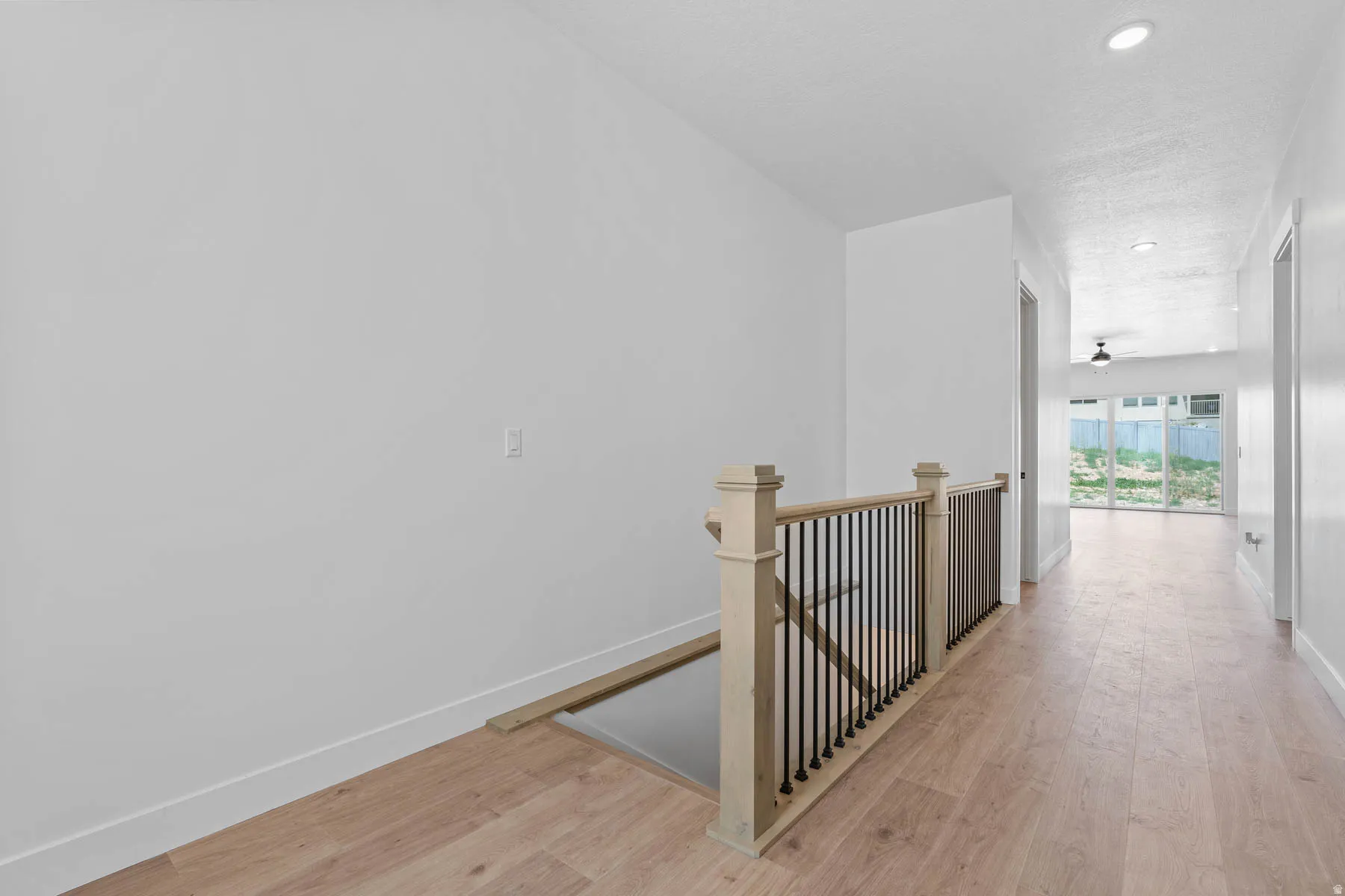 Hall with light wood-type flooring, an upstairs landing, and recessed lighting