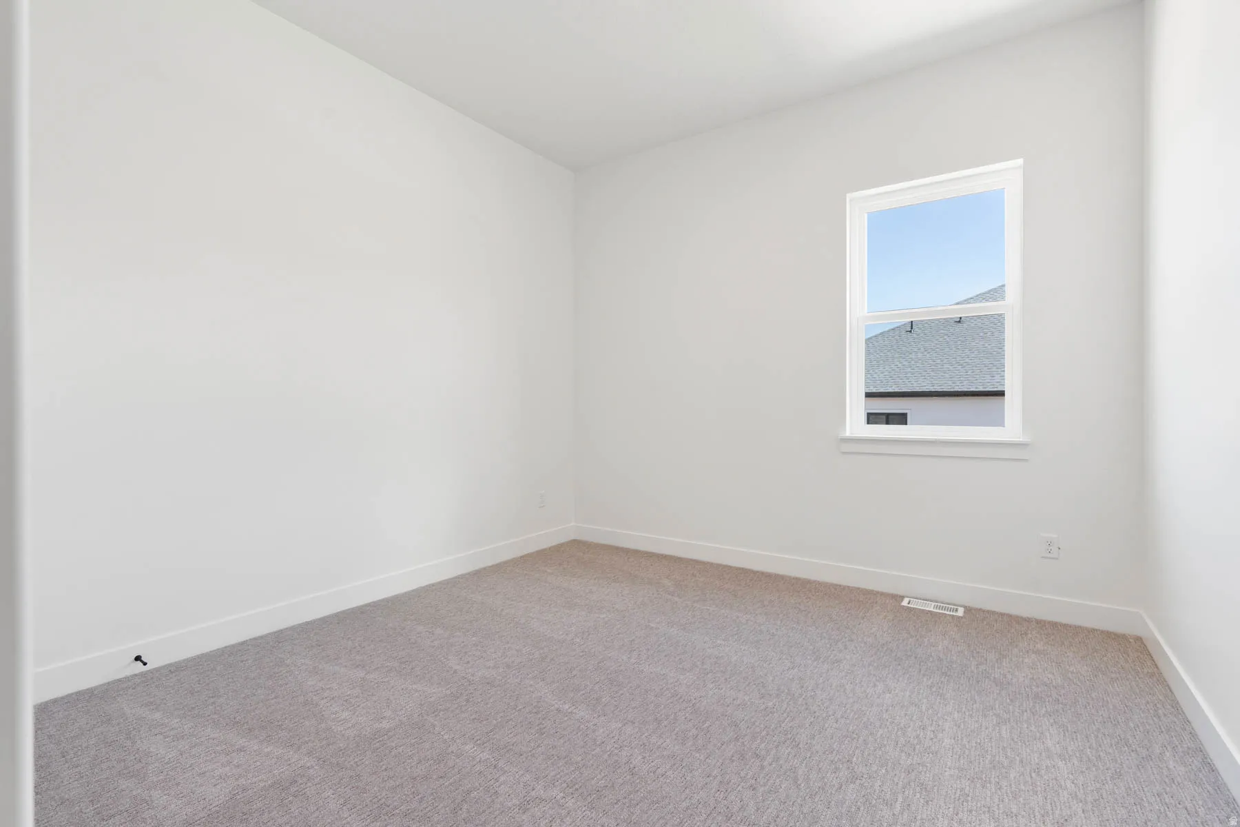Carpeted spare room featuring baseboards