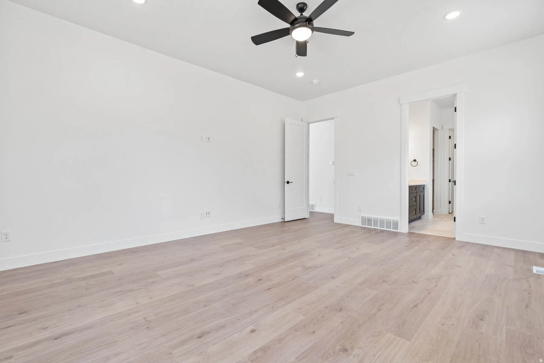 Unfurnished bedroom with light wood-type flooring, ceiling fan, recessed lighting, and ensuite bathroom