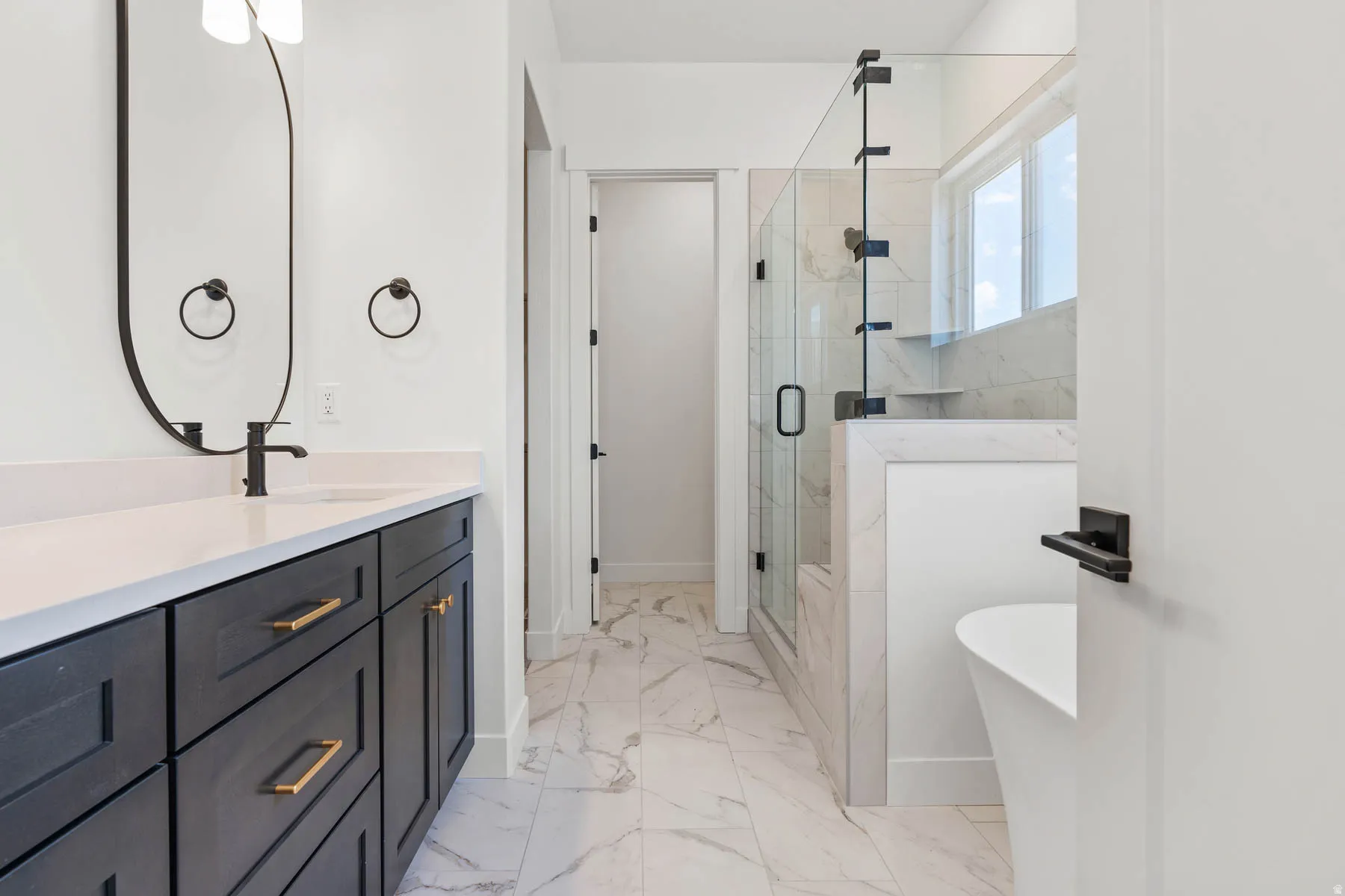 Bathroom with a marble finish shower, a soaking tub, vanity, and light marble finish flooring