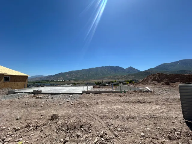 Building site featuring a concrete foundation, surrounding dirt terrain, and distant mountains