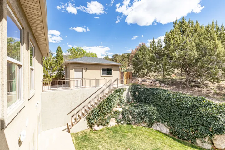 View of grassy yard featuring stairway and a balcony