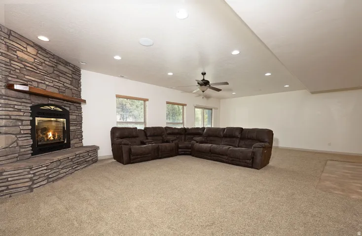 Living area with light colored carpet, a ceiling fan, a fireplace, and recessed lighting