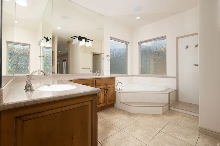 Full bathroom featuring double vanity, a garden tub, a stall shower, and light tile patterned flooring