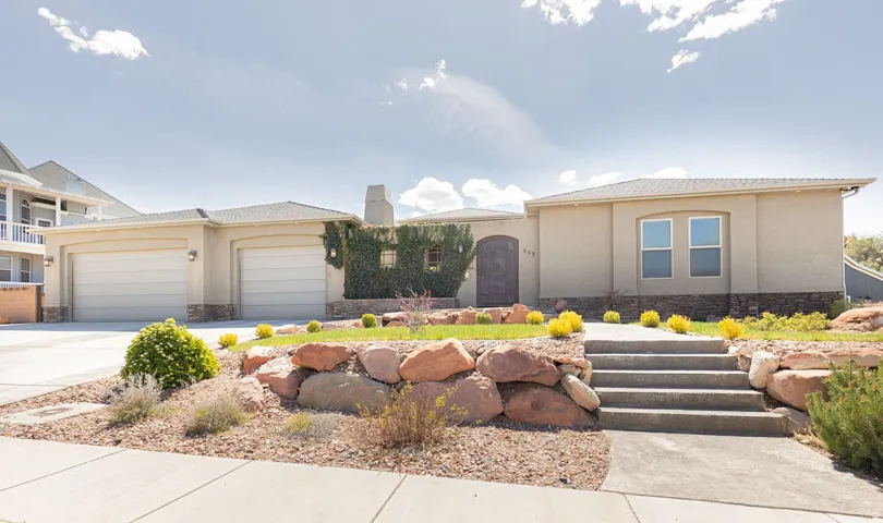 View of front of property featuring stone siding, a garage, stucco siding, concrete driveway, and a chimney