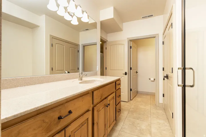 Full bathroom featuring vanity, light tile patterned floors, and a chandelier
