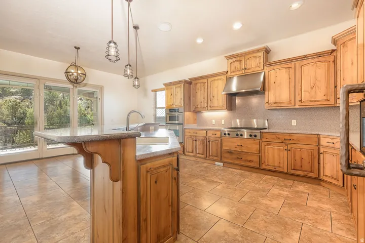 Kitchen featuring a kitchen island with sink, a kitchen breakfast bar, tasteful backsplash, hanging light fixtures, and stainless steel appliances
